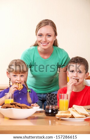 Young mother together with two children eat breakfast at kitchen