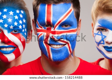Close up of painted faces. Three person with diffrent contries flag painted on their faces