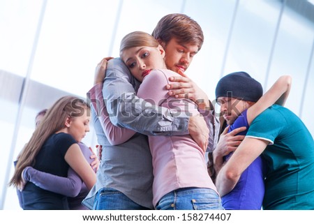 Three pair of people hugging each other. Girl with upset look on the foreground