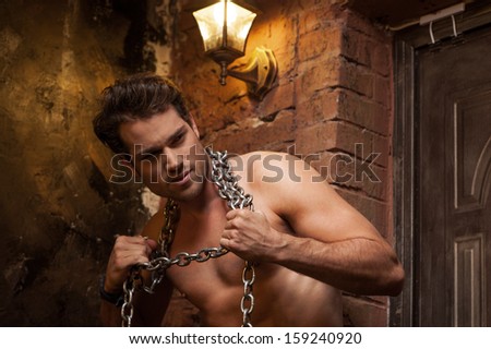 Sexy man with nude torso and chain on neck. Looking away