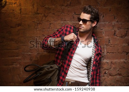 Stylish Sexy Man Looking Away. With Handbag On His Shoulder