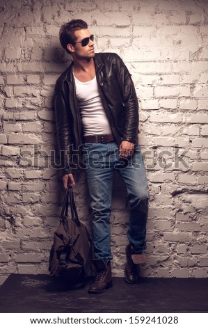 Sexy Man With Handbag. Standing In Black Leather Jacket And Jeans