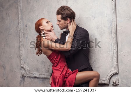 Handsome Man Is Going To Kiss His Beautiful Woman. Standing In Red Classical Dress