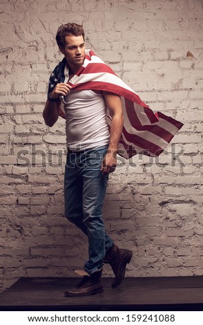 Handsome man walking using American flag like a cloak. Looking away