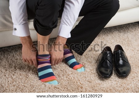 Close up of a man wearing colorful sock under classical business suite. Idea of being different