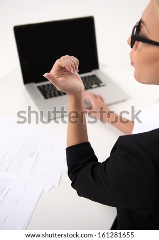 Woman looking at her nails while working at laptop. Close up shoot