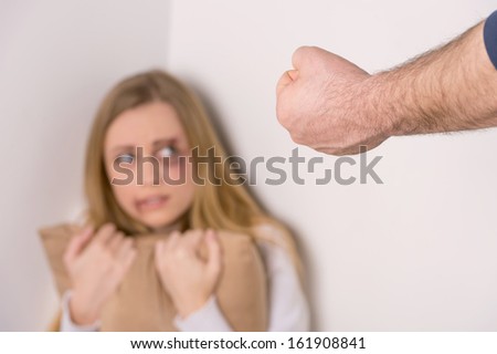 Close up of man fist. Scared injured woman face on background.