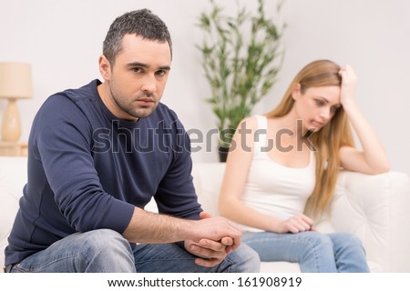 Sad depressed man on foreground. Scared sad woman on background