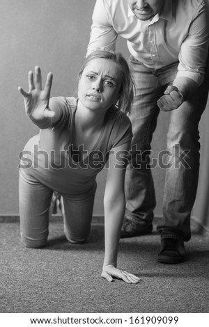 Women on her knee asking for a help. Wanting to be saved from male aggression. Black and white photo