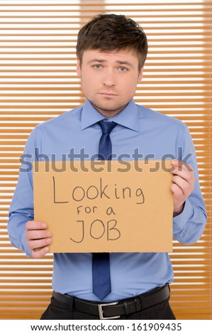 Sad unemployed man is looking for a job. Showing plate with sign
