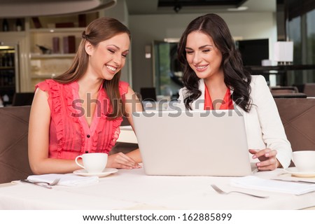Two female friends loathing reading funny posts in Internet. Or chatting with other friends