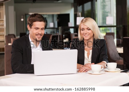 Business couple working with laptop at coffee. While having business lunch.