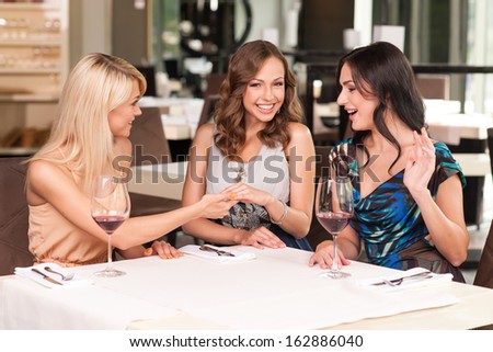 Three female friends celebrating that their friends getting married. Looking happy and surprised