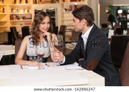Sexy couple at the romantic dinner. Looking at each other drinking wine