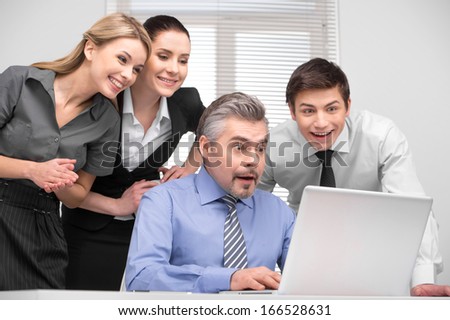 Surprised business team looking on laptop with laughing. Having fun at working place.