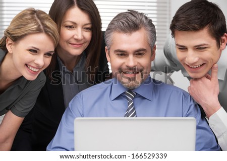 Close up of Smiling group of people looking at laptop. Looking happy and successful sitting in modern office