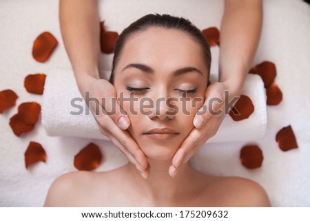 girl given massage on table. gentle face massage with flowers