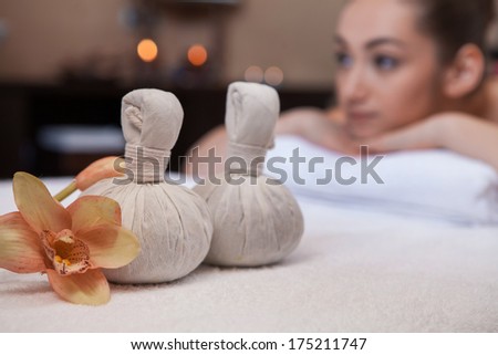textile massage spa pouches with flowers. pretty girl on background on massage table