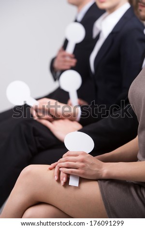 girl with beautiful legs sitting and voting. group of people holding cards with numbers