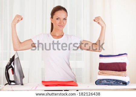 Portrait of smiling housewife ironing clothes. waist up housewife standing and showing muscles