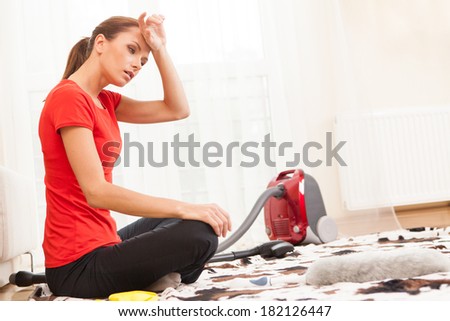 closeup of young brunette cleaning carpet. tired and exhausted girl sitting on carpet