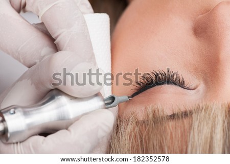 professional tattooist making permanent make-up. attractive lady getting facial care and tattoo