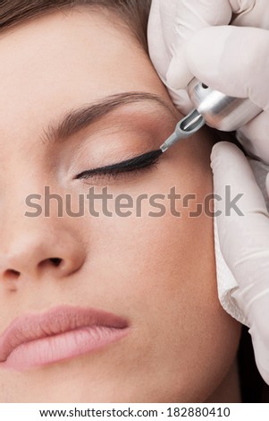 professional tattooist making permanent make-up. beautiful young woman getting tattoo