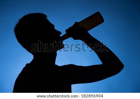 young man drinking alcohol from bottle. young drunkard holding bottle and standing