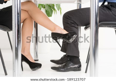 The Office Affair. Woman\'s foot looking for man\'s foot under a business table.