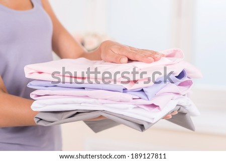 Stack of colorful clothes. Portrait of woman holding stack of clothes