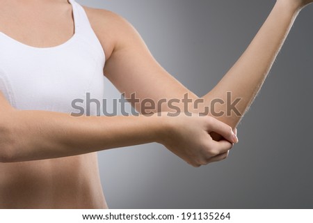 Elbow pain. Close up of woman with elbow pain isolated on gray background