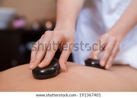 Stone treatment. Woman getting a hot stone massage at a day spa