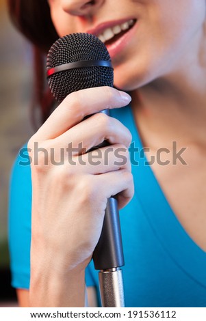 Woman singing karaoke. Closeup of woman singing into microphone
