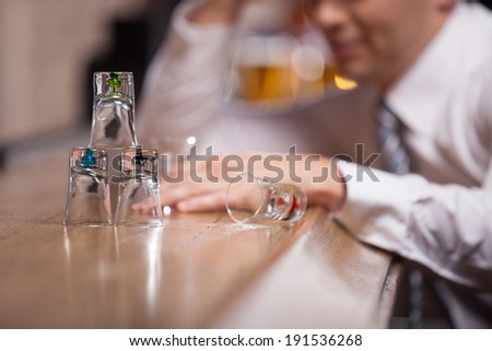 All Alone.  Man drowning in his sorrows drinking whiskey by himself at a bar.
