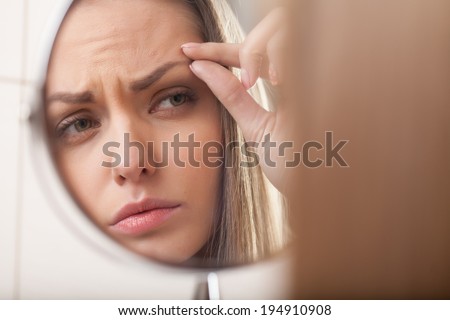 closeup of young woman looking into mirror. mirror reflection of beautiful girl eyebrow