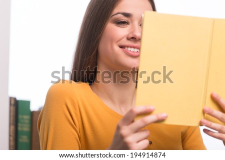 Beautiful young woman reading book. closeup of girl sitting on sofa at home