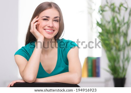 beautiful young girl leaning on chair. attractive woman sitting on stool and smiling
