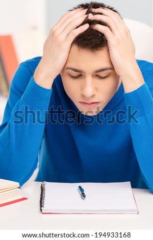 attractive young man studying lessons. handsome boy wearing blue sweater memorizing