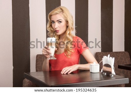 young attractive girl drinking cappuccino. beautiful lady sitting in cafe and looking