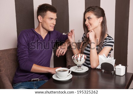 young couple eating ice-cream in cafe. attractive man and woman sitting in coffee shop