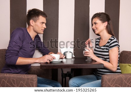 young man and woman talking in coffee shop. pretty girl and boy drinking coffee