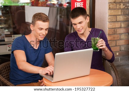 two man working on computer in cafe. handsome guy drinking and looking at screen