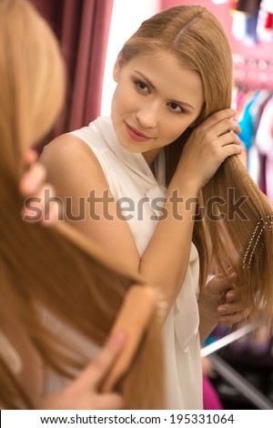 beautiful young girl combing hair. attractive blond woman looking into mirror