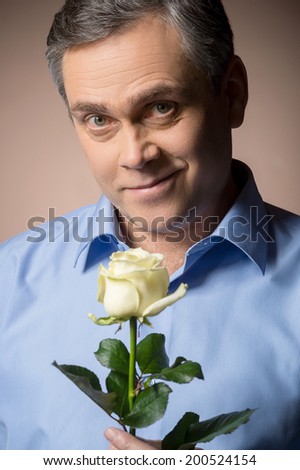 man holding white rose and smiling. closeup portrait of man with beautiful flower