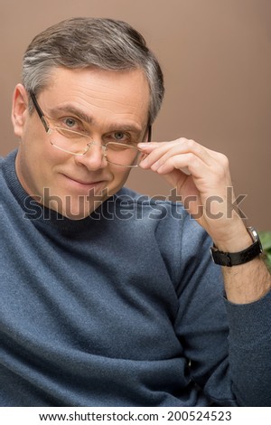closeup of older man looking into camera. man wearing glasses and watches and smiling