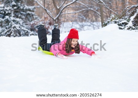girl sliding on snow from hill fast. child lying on sledges and doing down fast