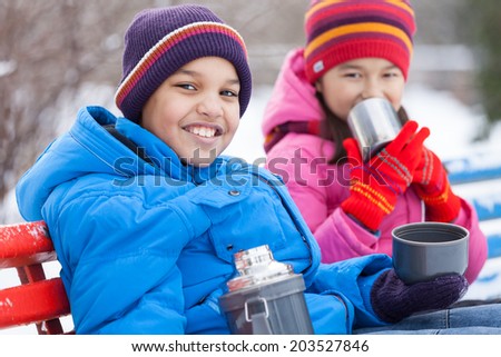 nice boy and girl sitting in park. two persons drinking hot tea outside