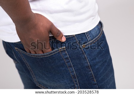 black man keeping hand in pocket. guy wearing white t-shirt and blue jeans