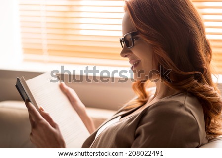 beautiful young woman reading book. cute girl sitting near window and smiling