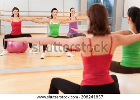 Pilates aerobics women group with stability ball. young girls sitting and looking into mirror gym